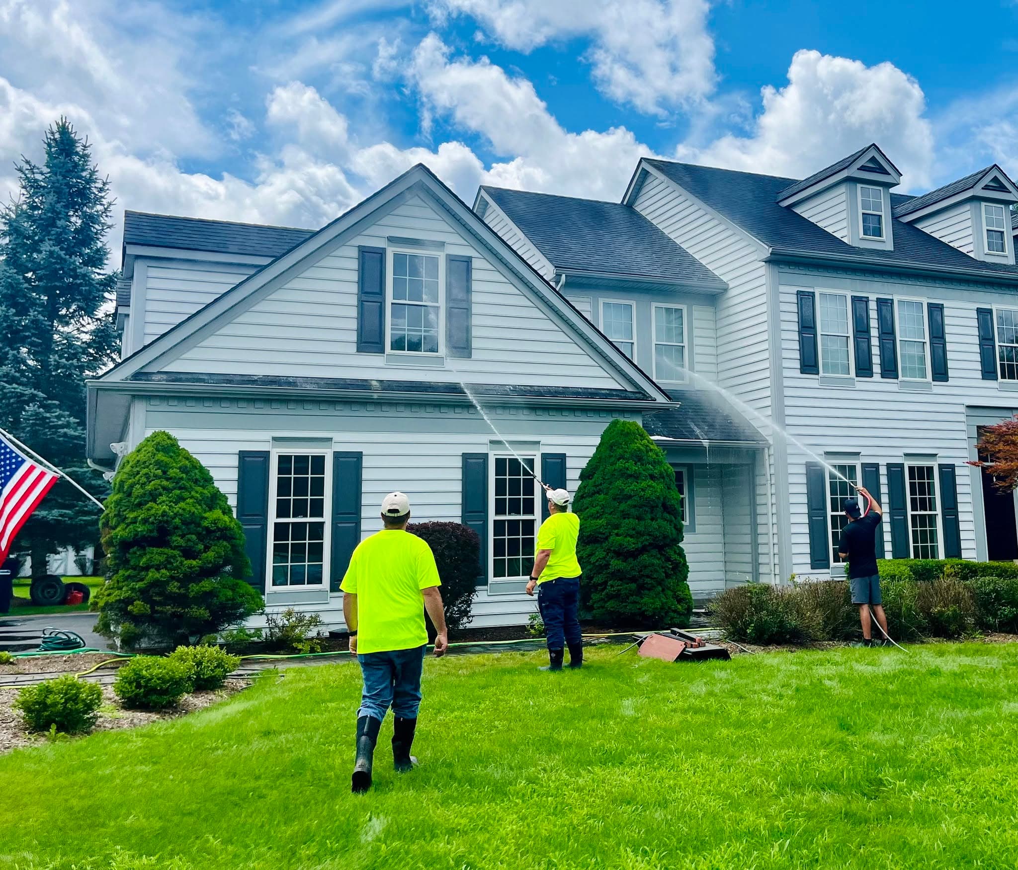 The Northern EcoWash crew soft washing a two-storey home's siding on a clear day