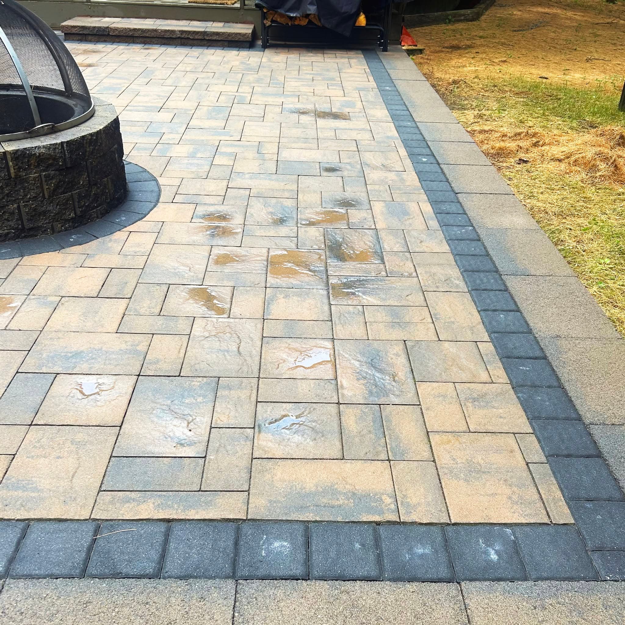 A cleaned stone paver patio with a fire pit and dark border pavers