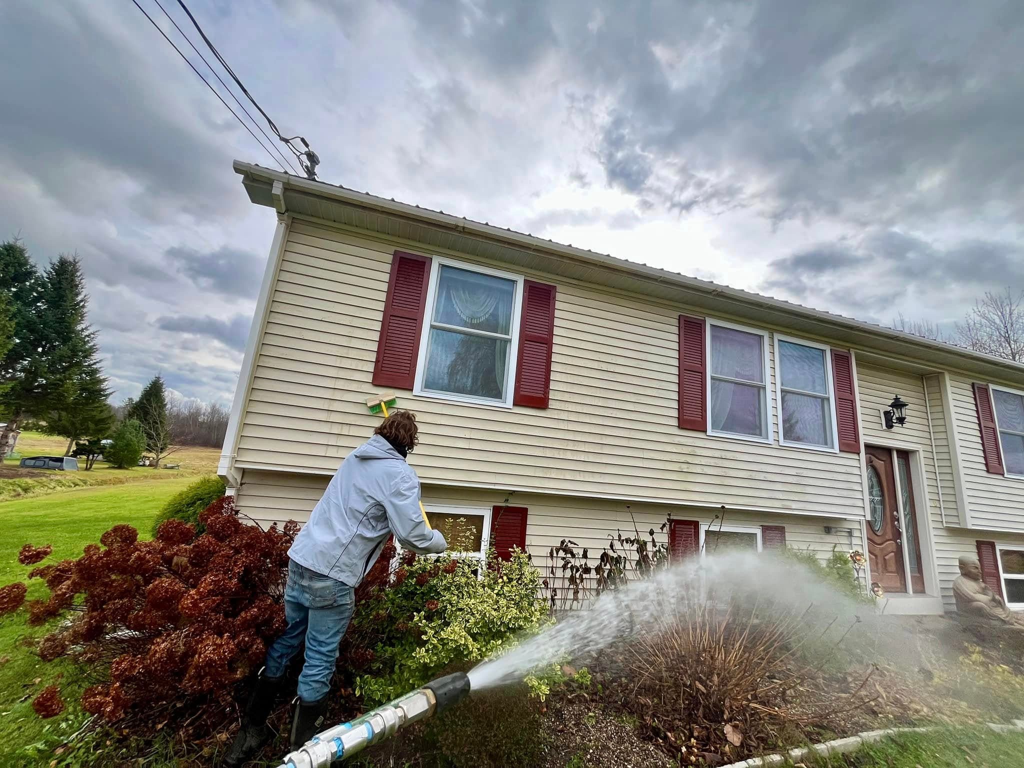 A Northern EcoWash technician spraying the upper storey and roofline of a house from the ground