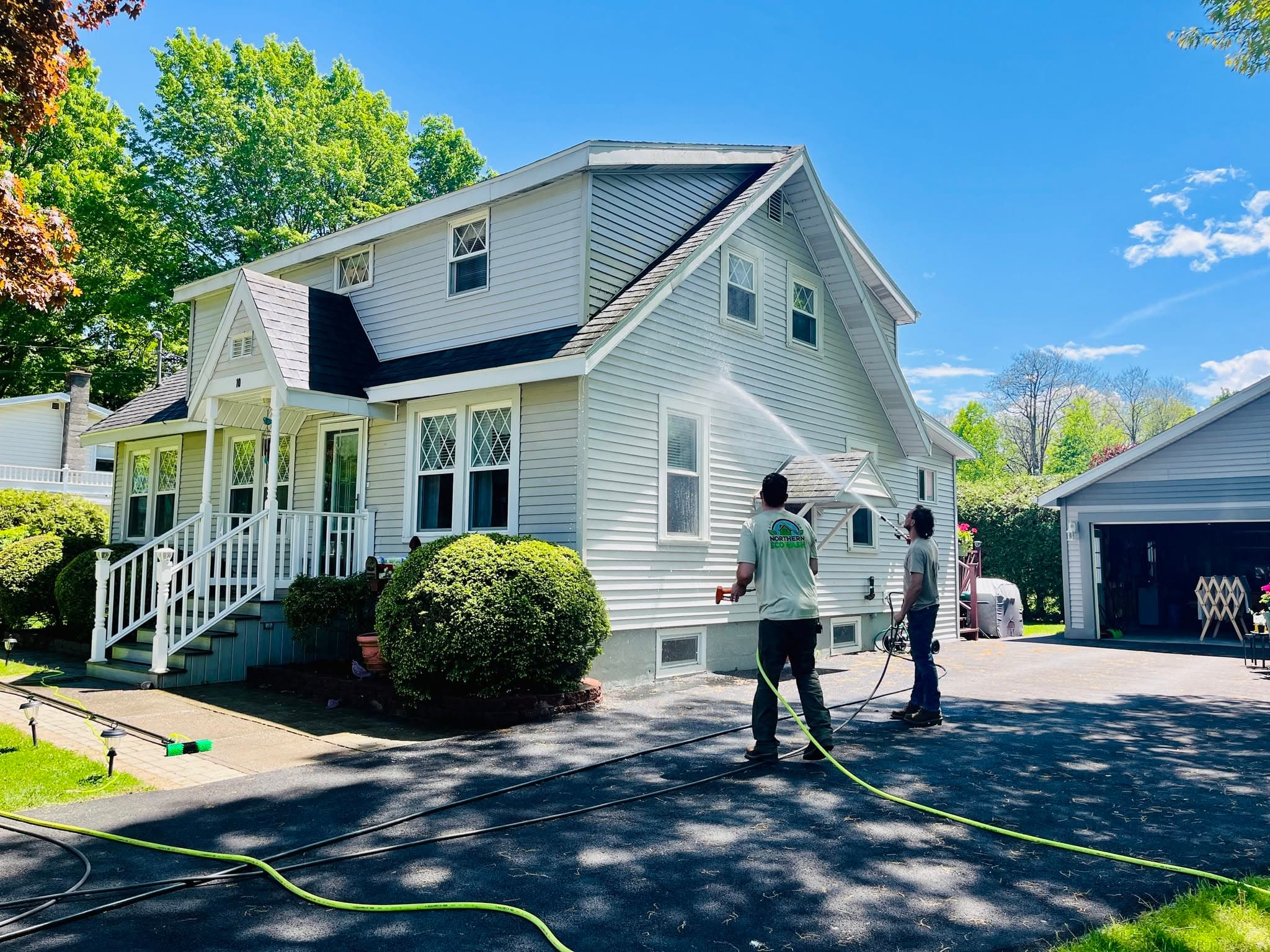 Northern EcoWash technicians soft washing the siding of a two-storey home